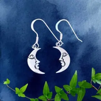 an image of a pair of sterling silver earrings that have a modest dangle. Each angle is a waning crescent moon shape with a face on it.