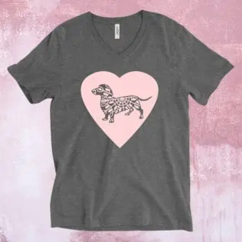 An image of a charcoal grey t-shirt with a large pink heart across the chest and a grey dachshund dog on the heart.