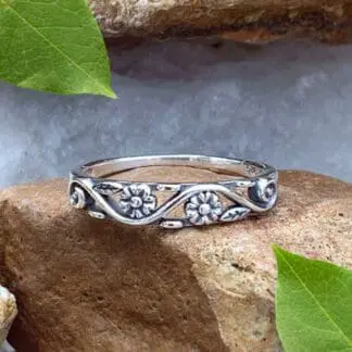 A photo of our Sterling Silver Dainty Double Flower Ring in a narrow filigree band with 3 delicate flowers and leaves amidst a swirl design with the back side being solid.