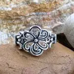 A sterling silver ring made of sections of oxidized sterling silver swirls going in a circular design to create a flower.