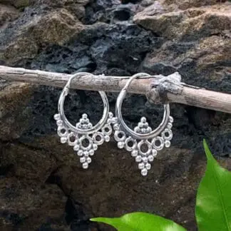 A photo of Sterling Silver Hoop Earrings with 6 little silver beads at the bottom inside of the hoop and a group of open silver circles with silver beads below the hoop going down into a point.