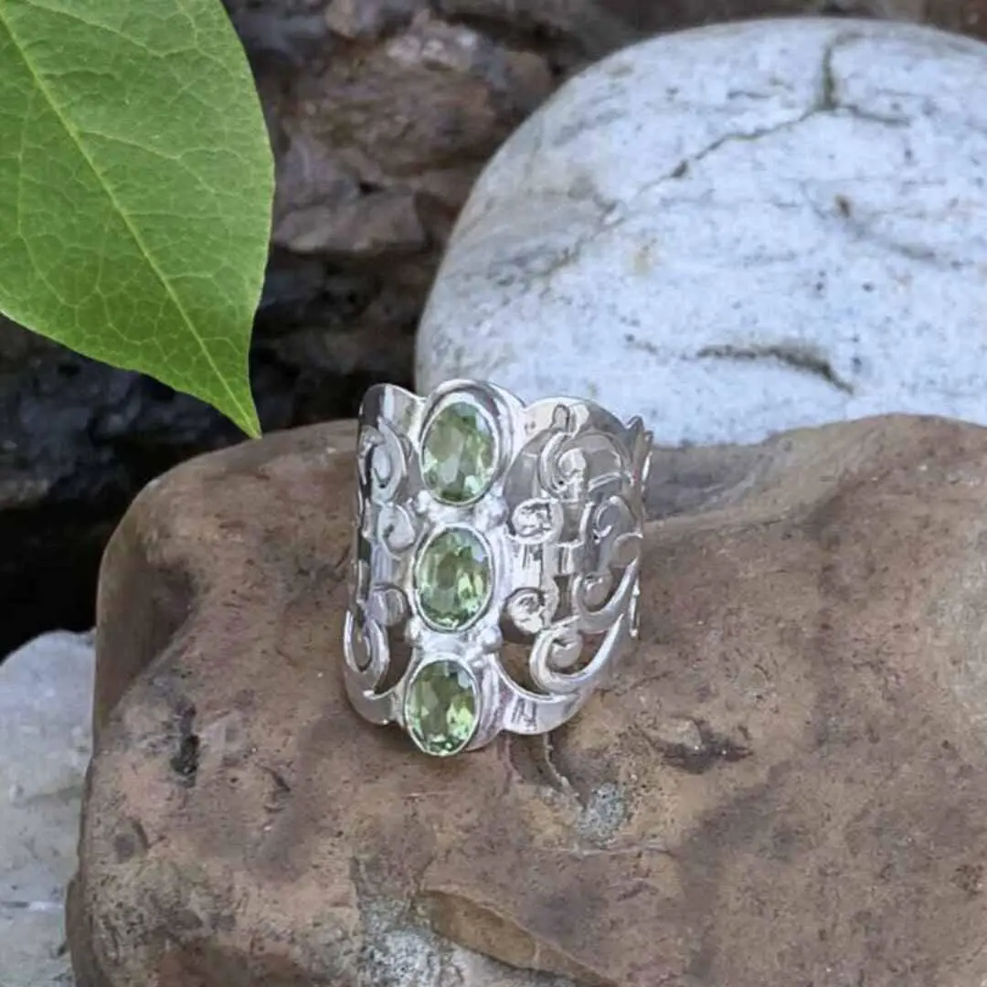 Wide Filigree Sterling Silver Ring with three faceted green Peridot gemstones in a vertical line on the front center.