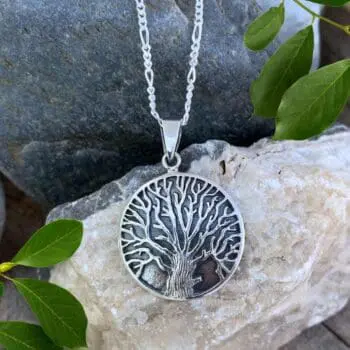 an image of a round sterling silver pendant with oxidation and a dramatic tree.