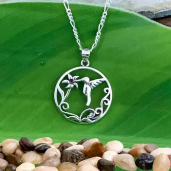 an image of a sterling silver pendant of a round circle with a hummingbird in flight drinking nectar from a blooming flower