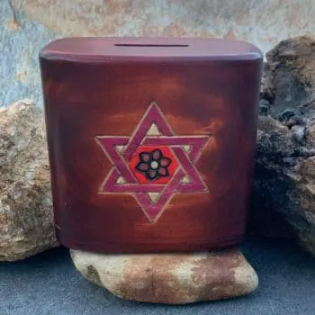 an image of a 4.50 x 2.50 x 4.25 inch brown wood box with a burgundy shaded star of David on the front and a coin slot on top. The box has a secret sliding panel on the bottom to open and close it.