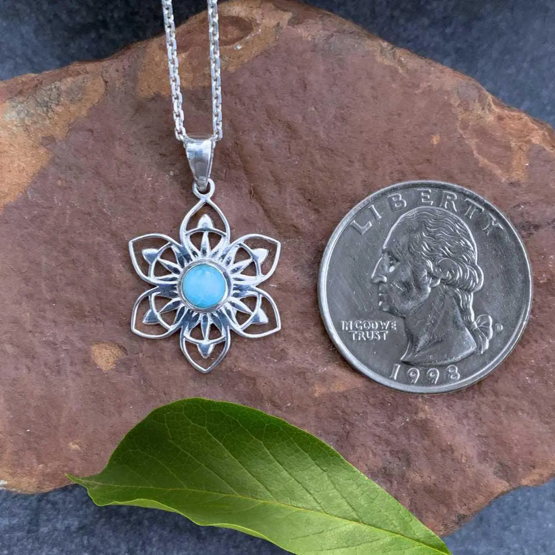 an image of a Sterling Silver Lotus with a round Larimar in the center Pendant next to a quarter