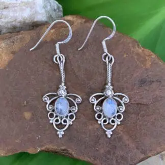 an image of a pair of Sterling Silver and Rainbow Moonstone Feminine Earrings with a 1.9 inch total drop and a lacy sterling filigree look around an oval rainbow moonstone.