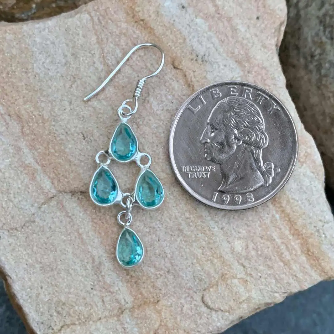 an image of a Blue Topaz and Sterling Silver Chandelier Earring with 4 teardrop shaped faceted blue topaz gemstones next to a quarter