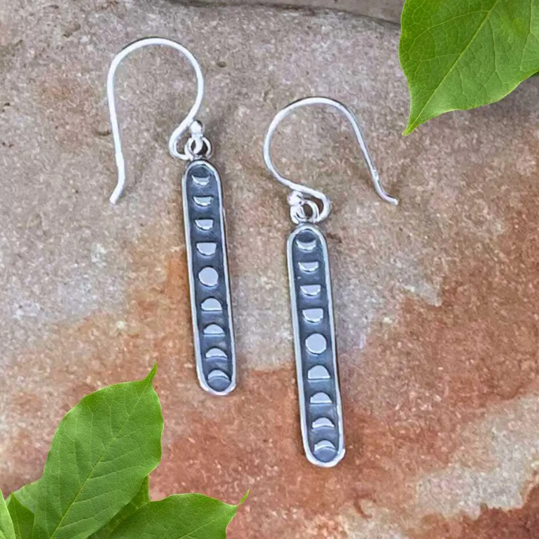 an image of a pair of Sterling Moon Phases Earrings shaped in a long vertical oval with the phases of the moon