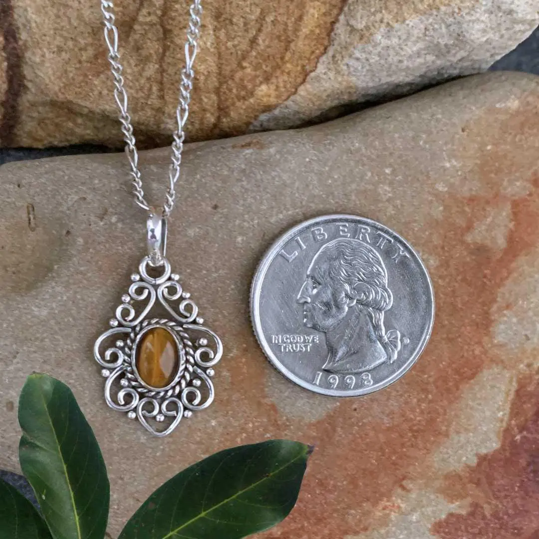 an image of a Filigree Sterling Silver and Tiger's Eye Pendant next to a quarter