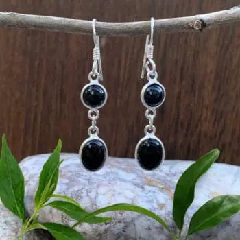 an image of a pair of dangle earrings with a smaller round black onyx cabochon and below it a larger oval black onyx cabochon all set in sterling silver