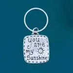 an image of a rectangle shaped pewter keychain that says You Are My Sunshin and has a little sun