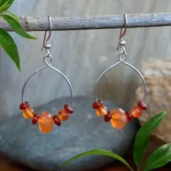 an image of a pair of Carnelian and Sterling Silver Dangle Hoop Earrings. There is an open circle with some carnelian beads on it and the hoop hangs from an ear hook