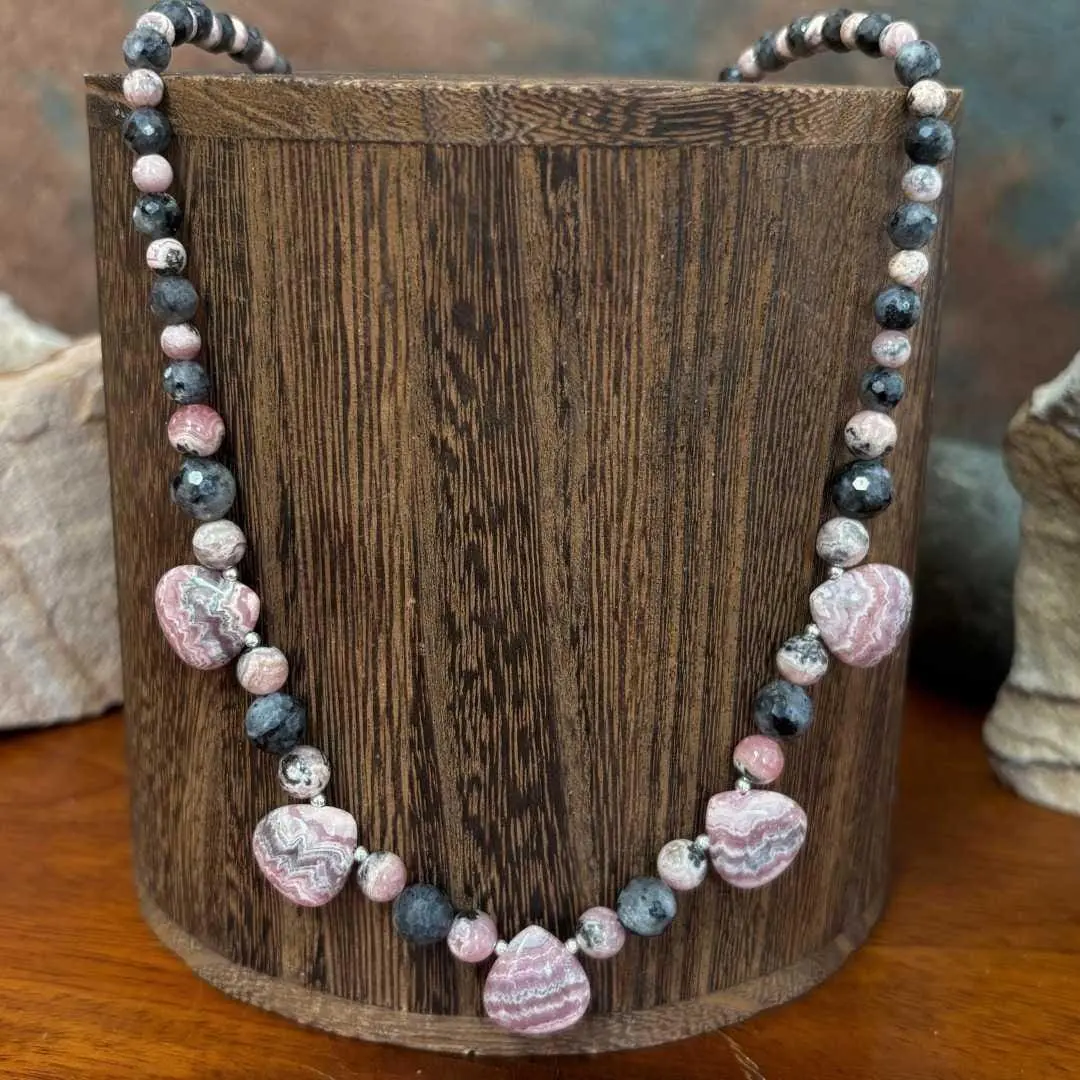 an image of a Rhodochrosite Teardrops and Larvikite Necklace featuring 5 teardrop shaped rhodochrosite beads accented with a mix of faceted grey larvikite beads and rhodochrosite beads offering a lovely combination of the pinks and greys. The necklace is 18.875 inches long.