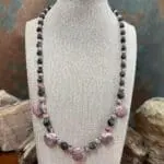an image of a Rhodochrosite Teardrops and Larvikite Necklace featuring 5 teardrop shaped rhodochrosite beads accented with a mix of faceted grey larvikite beads and rhodochrosite beads offering a lovely combination of the pinks and greys. The necklace is 18.875 inches long.