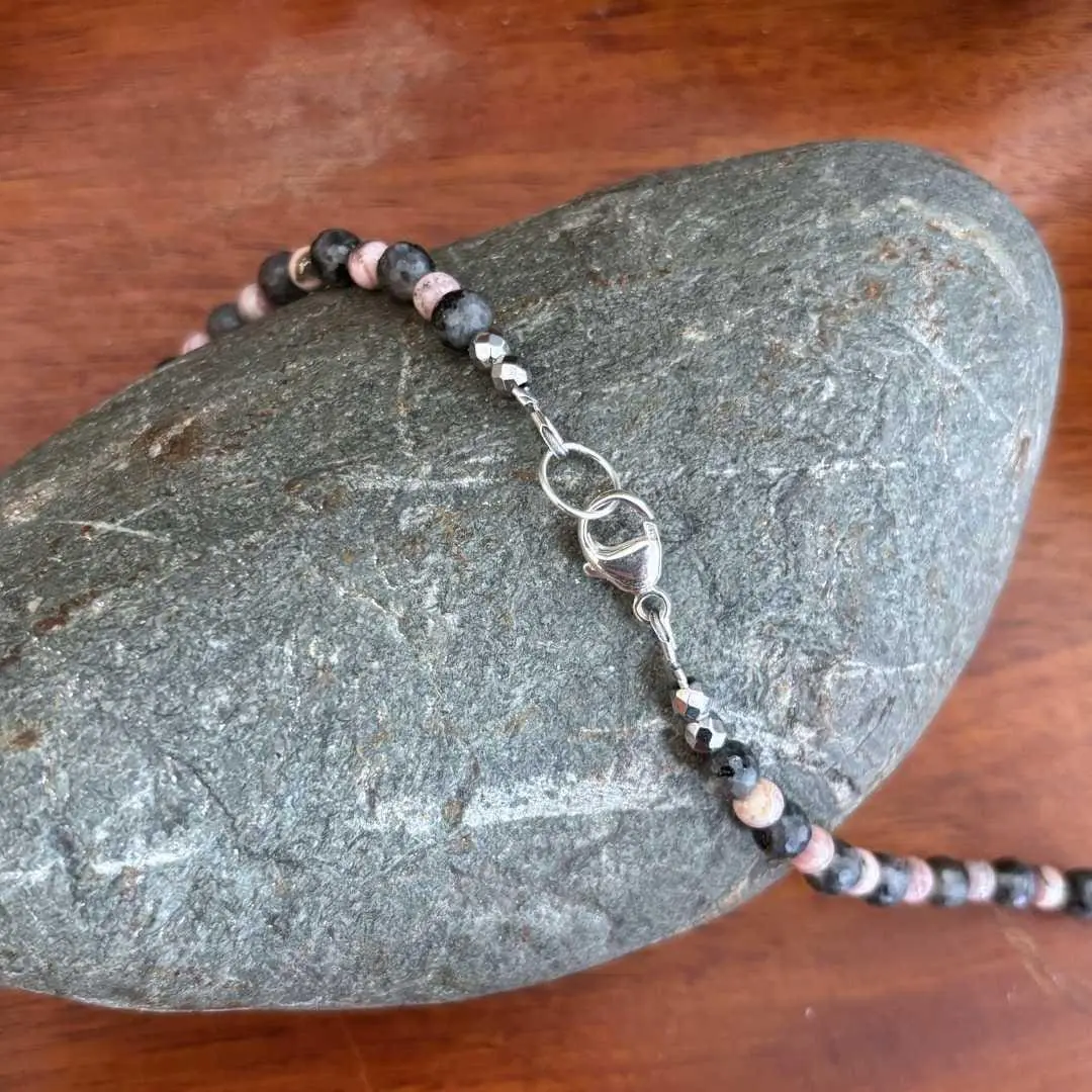 an image of a Rhodochrosite Teardrops and Larvikite Necklace featuring 5 teardrop shaped rhodochrosite beads accented with a mix of faceted grey larvikite beads and rhodochrosite beads offering a lovely combination of the pinks and greys. The necklace is 18.875 inches long. This image shows the sterling silver lobster clasp.