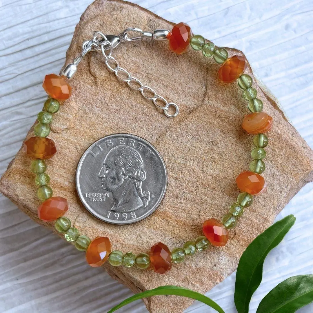 an image of a Carnelian and Peridot Beaded Bracelet with faceted rondelle carnelian beads alternating with trios of small peridot beads. This image shows the bracelet next to a quarter