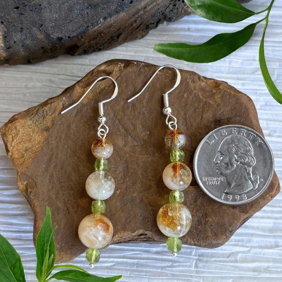 An image of a pair of Citrine and Peridot Beaded Earrings with three graduated round citrine beads separated by three small faceted cube shaped peridot beads. They are on a sterling silver ear hook.