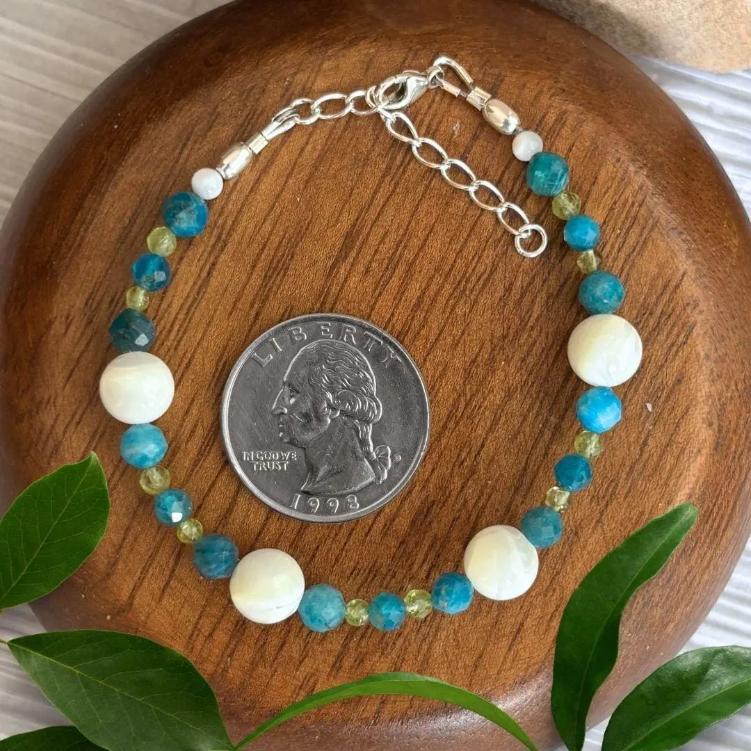 an image of a Mother of Pearl with Apatite and Peridot Bracelet next to a quarter