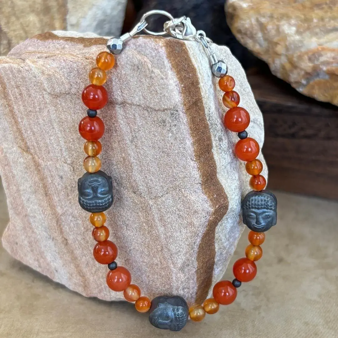 an image of a Gemstone beaded bracelet with 3 hematatite grey buddha head beads and orange and golden carnelian beads