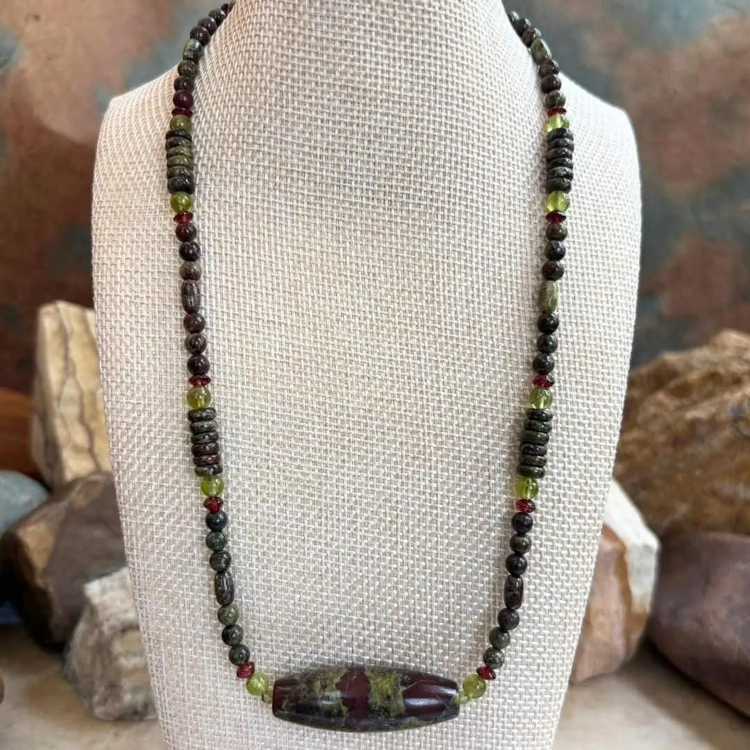 an image of a Dragon Blood Jasper with Peridot and Garnet Gemstone Necklace featuring a large barrel bead of dragon blood jasper with accents of small rondelle garnets and round peridot beads and assorted shapes of dragon blood jasper beads.