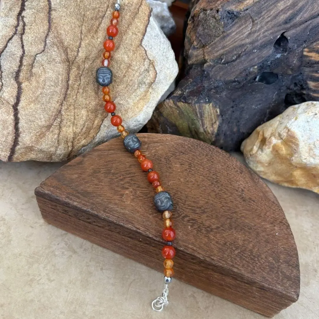 an image of a Gemstone beaded bracelet with 3 hematatite grey buddha head beads and orange and golden carnelian beads