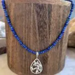 an image of a Lapis Lazuli Beaded Necklace with Horse Pendant featuring two sizes of small round smooth lapis beads with small rondelle beads. The focal point is a silhouette filigree teardrop shaped pendant of a horse's head in sterling silver.