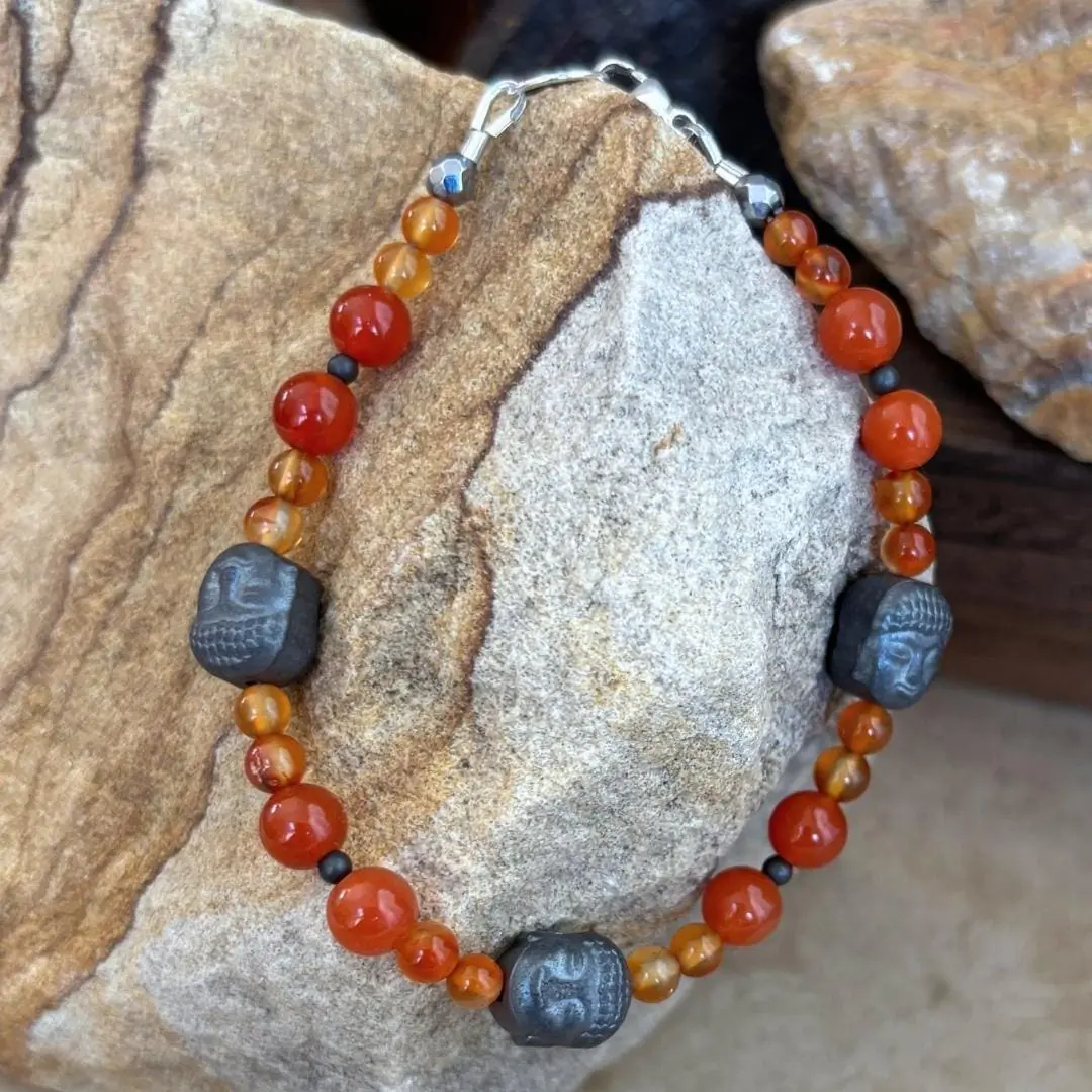 an image of a Gemstone beaded bracelet with 3 hematatite grey buddha head beads and orange and golden carnelian beads