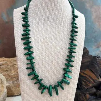 an image of a Malachite Sticks Beaded Necklace. It is an 18" necklace featuring malachite graduated smooth sticks alternating with 4mm round malachite beads and 3 tube malachite beads at the top of each side of the neck. It has a sterling silver lobster clasp.