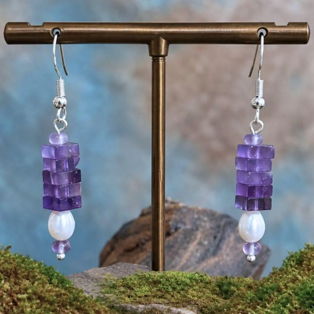 an image of a pair of Square Stacked Amethyst with Pearl Earrings with five 3 x 6 mm square beads stacked on top of a freshwater pearl and framed with a small amethyst rondelle bead on top and bottom. They hang on a sterling silver ear hook.