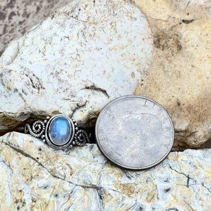 Oval Rainbow Moonstone in Sterling Silver Ring with Swirl on each side next to a quarter to show perspective of size