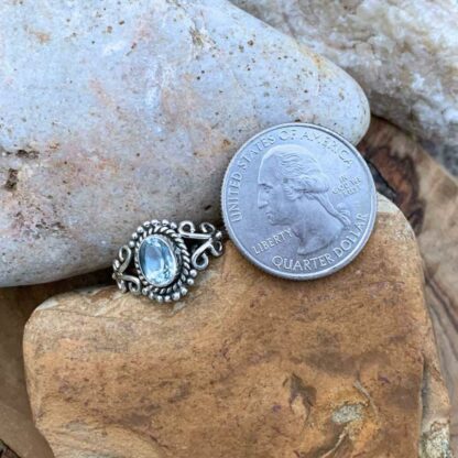 Oval Blue Topaz and Sterling Silver Dainty Ring Next to Quarter