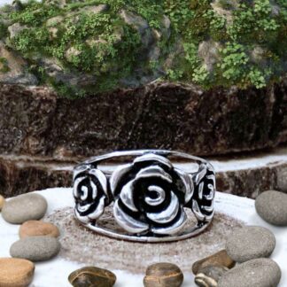 A picture of our sterling silver Triple Rose Ring featuring one large blooming sterling silver rose in the center with a smaller blooming rose on each side. The roses sit between open bands of sterling silver and roses have oxidation to give them depth. At the widest part it measures .47 inches.