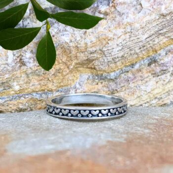 An image of a dainty sterling silver band style ring with hearts that wrap all the way around.