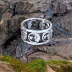 A picture of a half moon wrapping around an open area with a star inside each moon. The design is in sterling silver and repeat wraps around the band style ring several times.