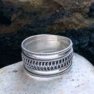 This is a picture of our unisex Bali Woven Sterling Ring that is a wide band of .51 inches with a braided section wrapping around the center of the ring.