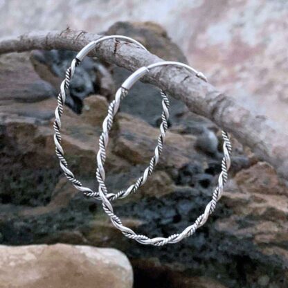 A photo of Sterling Silver large oval hoop earrings of rope like twisted sterling.