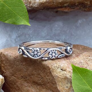 A photo of our Dainty Double Flower Ring in a narrow filigree band with 3 delicate flowers and leaves amidst a swirl design with the back side being solid.