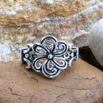 A sterling silver ring made of sections of oxidized sterling silver swirls going in a circular design to create a flower.