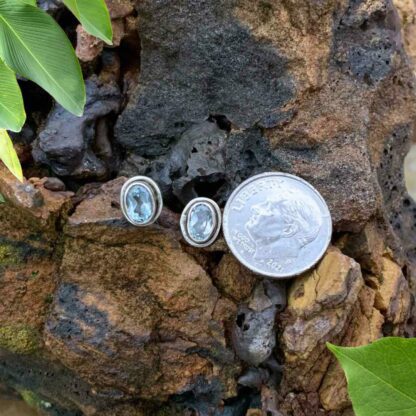 Oval Blue Topaz Stud Earrings in Sterling Silver Setting next to a dime for perspective