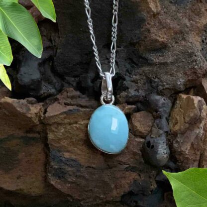 A Dainty Larimar oval pendant in a simple sterling silver setting. The pendant is .47 inches wide with a total drop of .94 inches. The stone is an oval freeform shape.