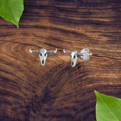 A picture of a pair of sterling silver longhorn skull stud earrings.