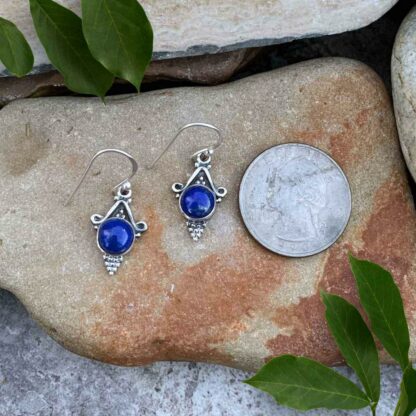 Round Lapis Lazuli Blue Gemstone in sterling silver setting with silver beads coming to a point below the stone. Sterling Fish hook style. Slight dangle. Earrings laying next to a quarter