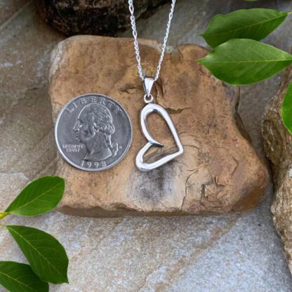 Sterling Silver Side Angled Open Heart Pendant that has a total drop of .63 inches and is next to a quarter