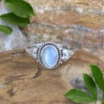 An image of our Oval Rainbow Moonstone and Sterling Silver Ring With a Heart on each side of the stone