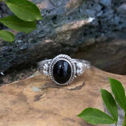 An image of an Oval Black Onyx and Sterling Silver Ring with a silver heart on each side.