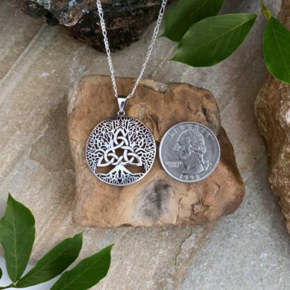 An image of our Sterling Silver Triquetra and Tree of Life Pendant next to a quarter. Total drop of pendant is 1.10 inches