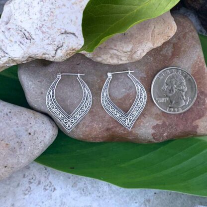 An image of our Elegant Sterling Silver Click Hoop Earrings with a bohemian oxidized pattern that come down to a curved vee. Earrings are next to a quarter