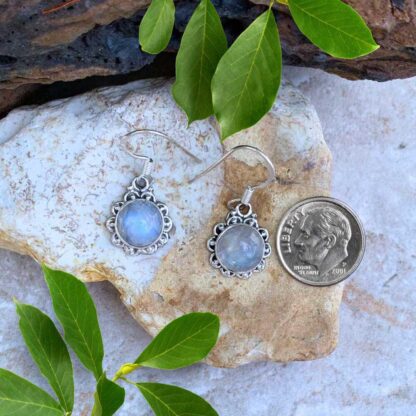 an image of a pair of Round Rainbow Moonstone and Sterling Silver Earrings. The round stone has a sterling silver scallop design surrounding it.