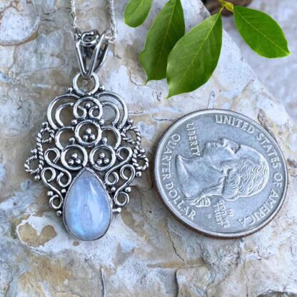 An image of a pendant with a group of sterling silver swirls and circles with a teardrop shaped rainbow moonstone pendant at the bottom.